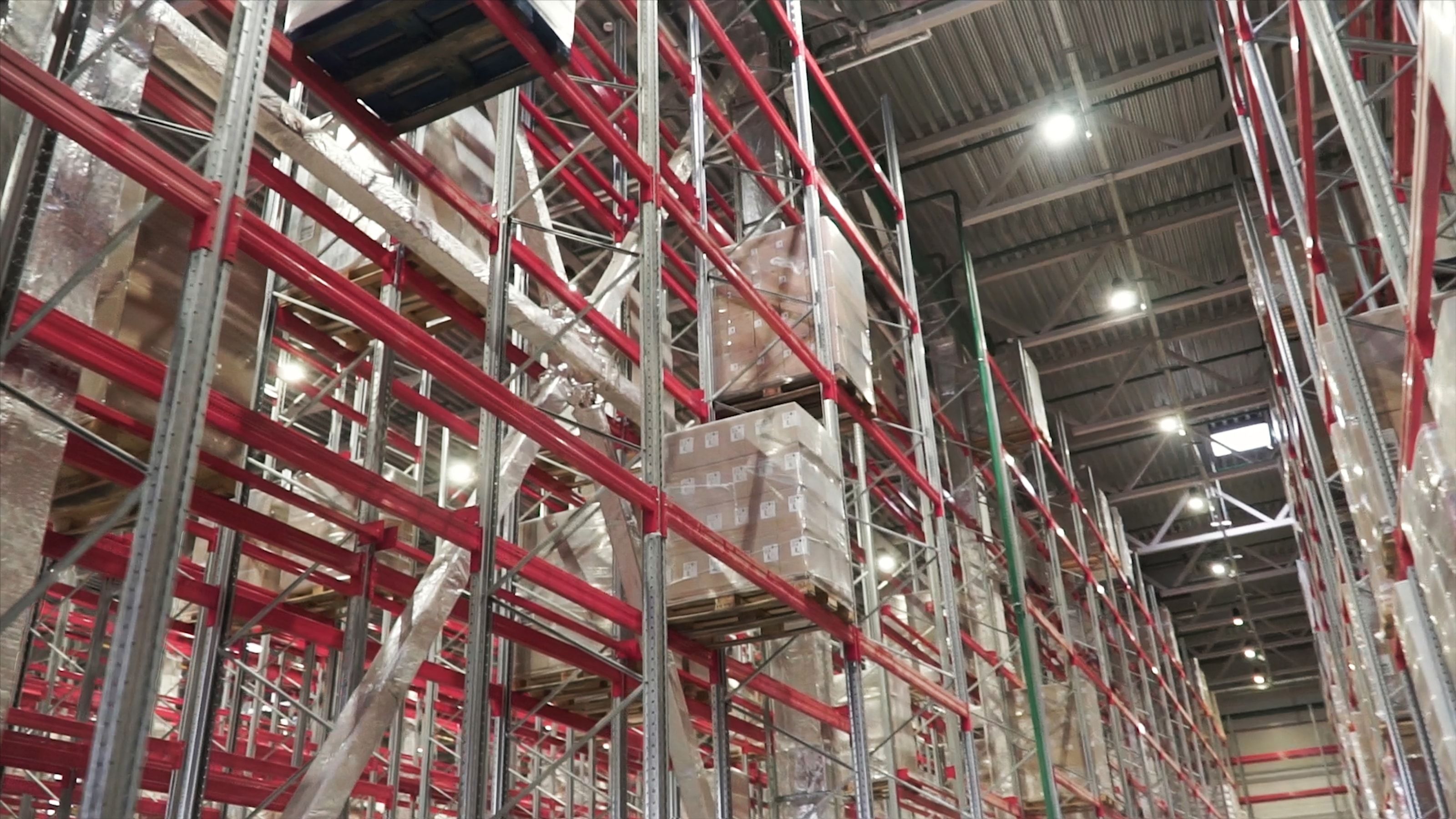 Interior de nave logistica industrial con racks de almacenamiento y sistema de rociadores en techo